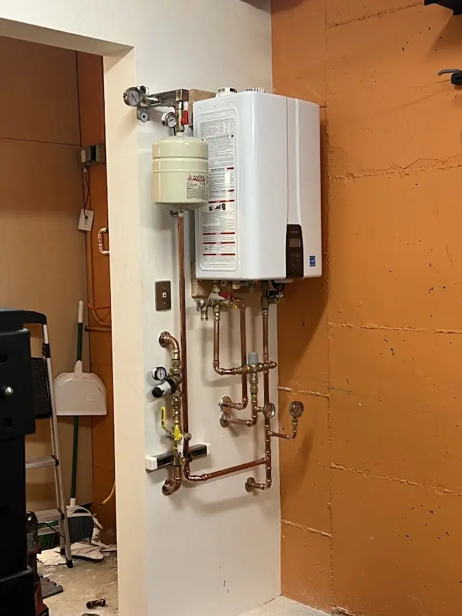Plumbing technician inspecting water heater connections in Kirtland AFB